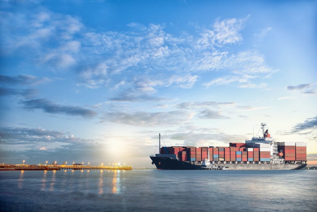 A massive container ship docking at a port during sunset, symbolizing the global logistics network and CLAH Ecosystem's strategic expansion to support international growth.