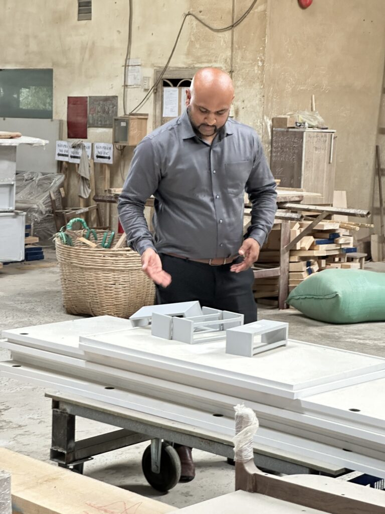 CLAH's Interior Production Quality Control Lead inspecting white furniture components at a manufacturing facility in Vietnam to ensure high standards of craftsmanship and technical precision.